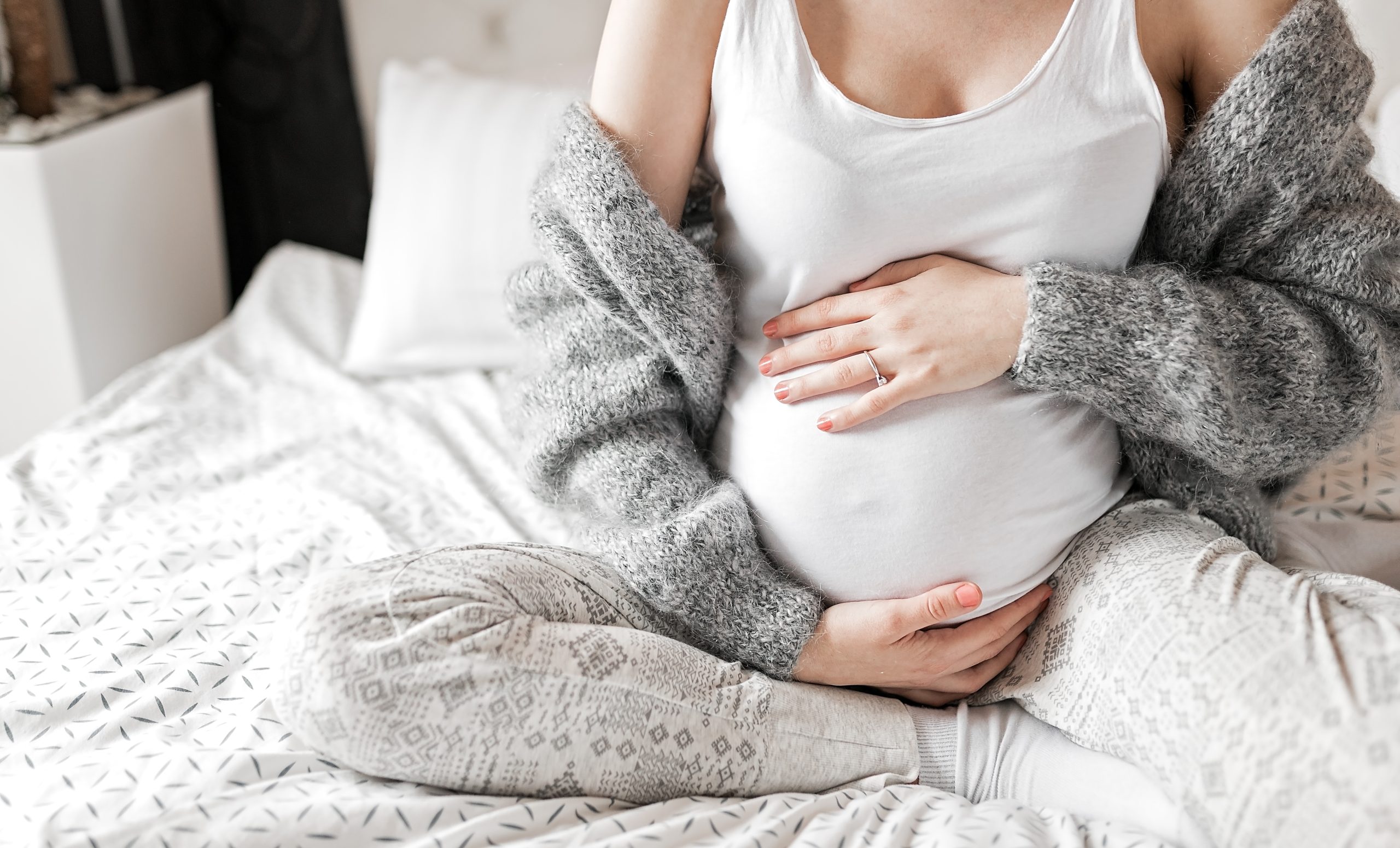 Eine schwangere Frau in entspannter Pose, hält liebevoll ihren Babybauch.